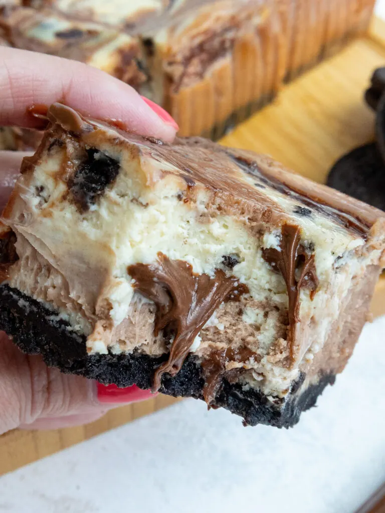 image of nutella cheesecake bar that's been bitten into to show it's nutella swirls