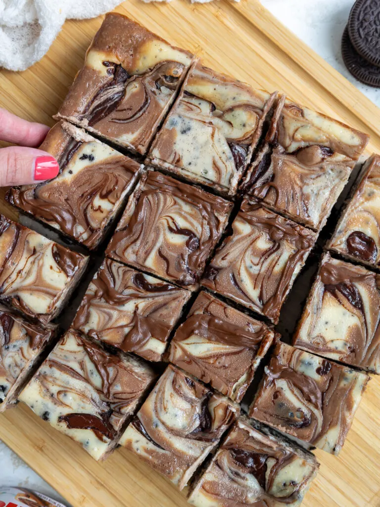 image of nutella cheesecake bars that have been cut on a wooden cutting board