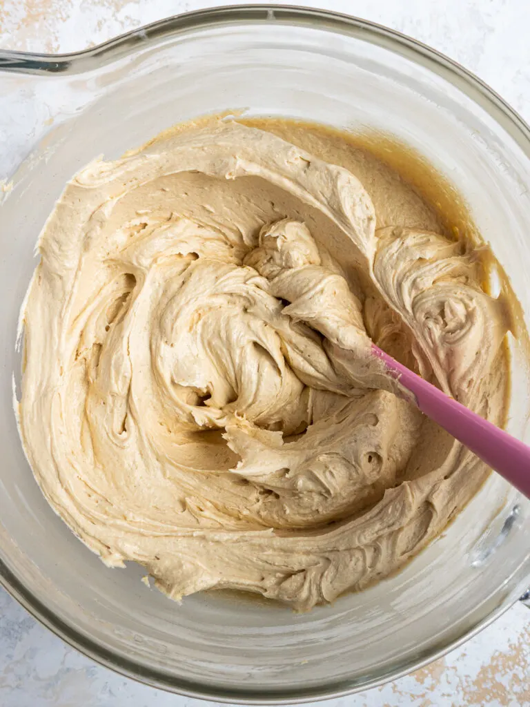 image of peanut butter buttercream frosting that's been made in a glass mixing bowl