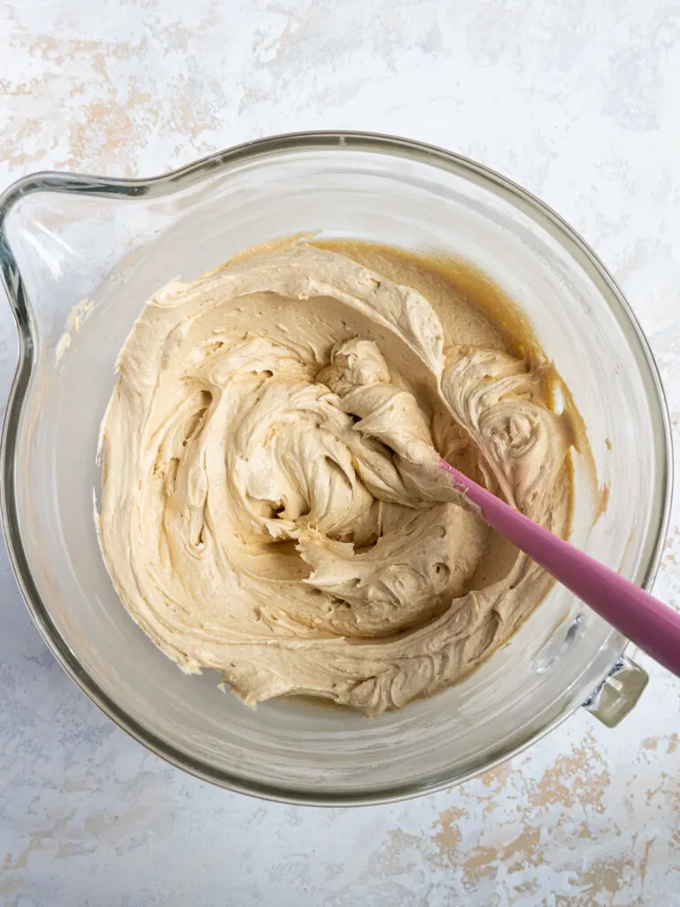 image of peanut butter buttercream frosting that's been made in a glass mixing bowl