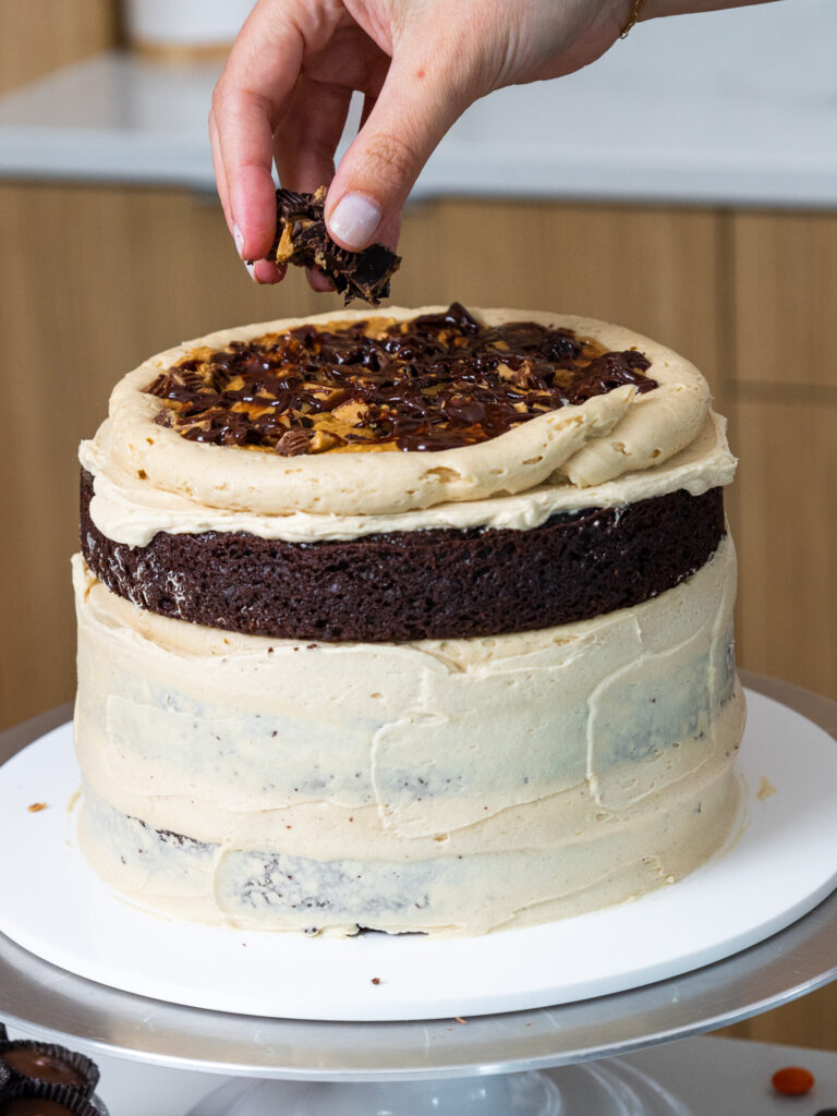 image of a reese's peanut butter cake being filled with peanut butter cups and chocolate ganache