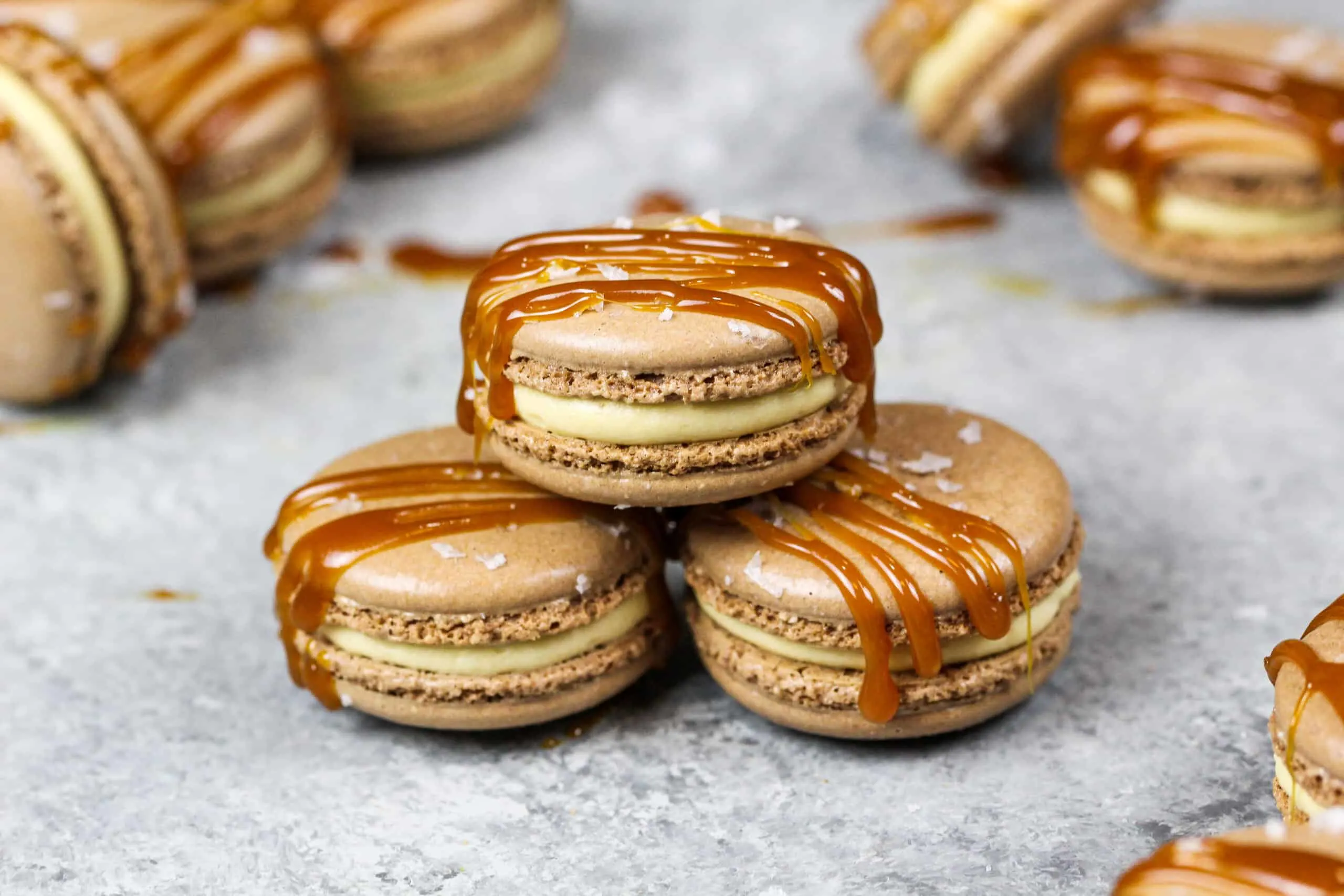 image of salted caramel macarons drizzled with caramel sauce and flakey sea salt