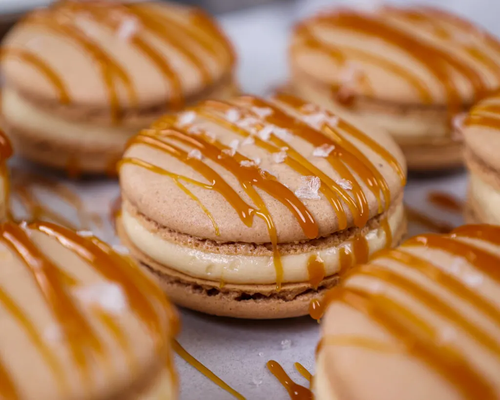 image of a salted caramel macarons decorated with a drizzle of caramel and a sprinkle of flakey sea salt