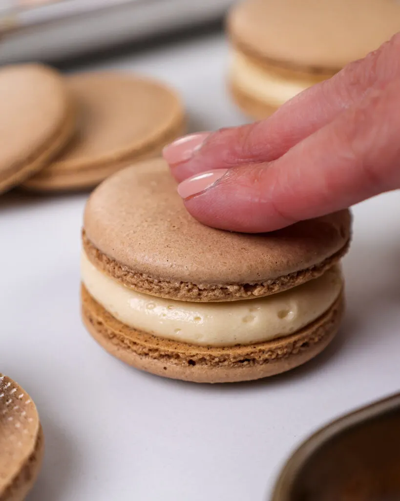 image of chocolate macaron shells that have been filled with caramel buttercream