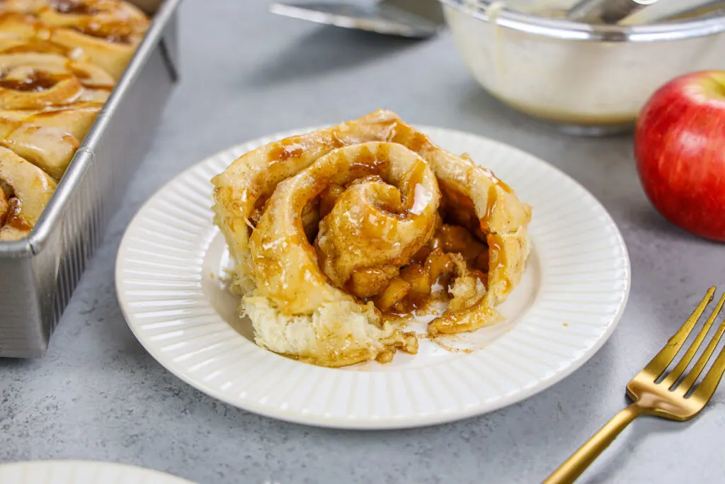 image of a caramel apple cinnamon roll that's been cut into the show it's delicious filling