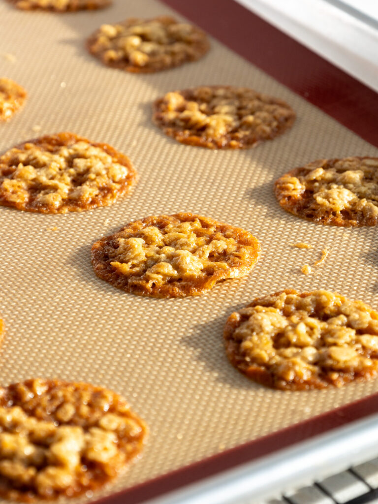 image of baked oatmeal lace cookies on a baking sheet that are cooling