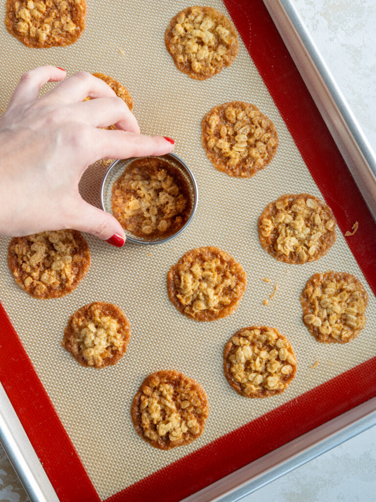 image of oatmeal lace cookies being reshaped with a circle cookie cutter