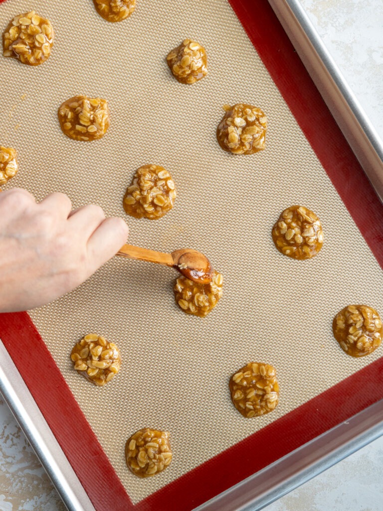 image of oatmeal lace cookie batter being spooned onto a silicone mat to be baked