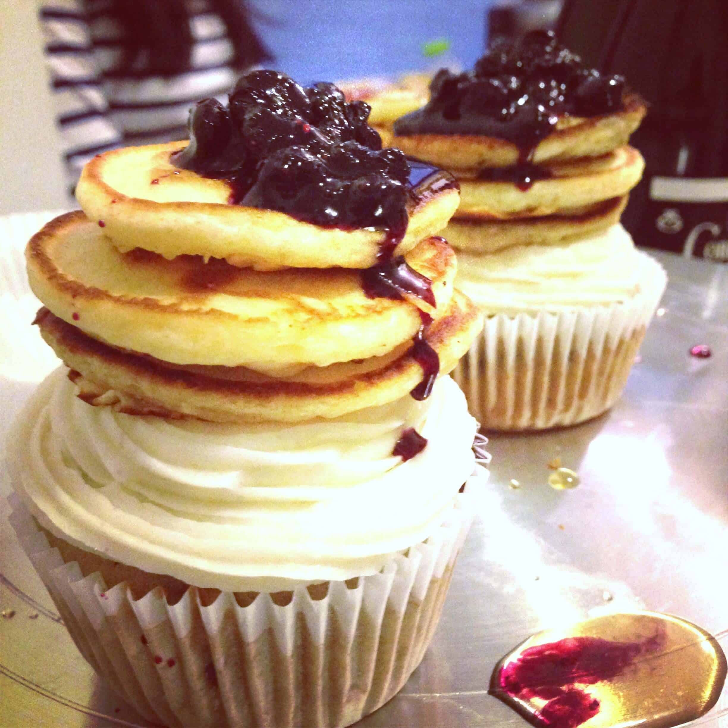 image of pancake cupcakes decorated with mini pancakes and a blueberry reduction