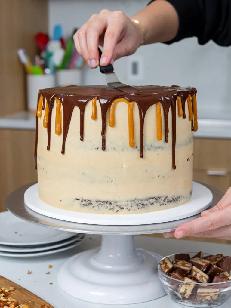 image of chocolate drips being added around a snickers cake