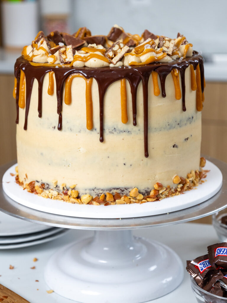 image of a chocolate snickers cake that's decorated with chocolate and caramel drips