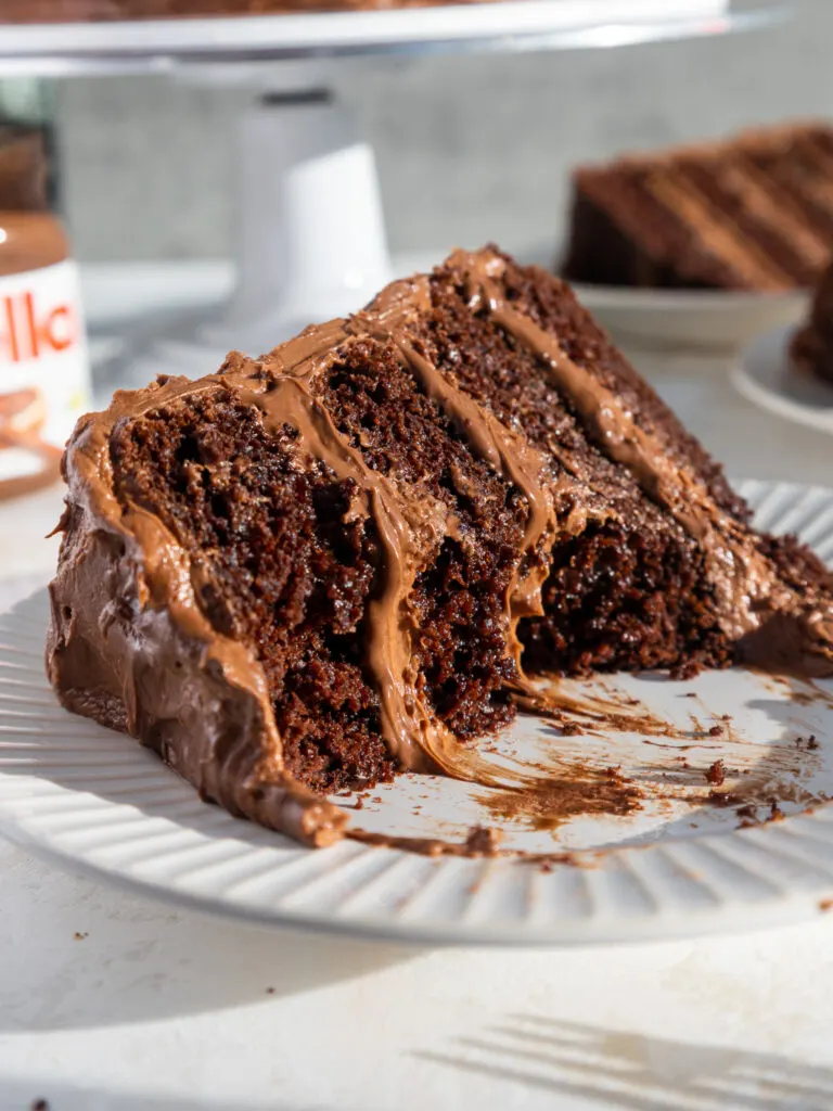 image of a slice of Nutella cake on a plate that's been cut into to show its Nutella buttercream filling