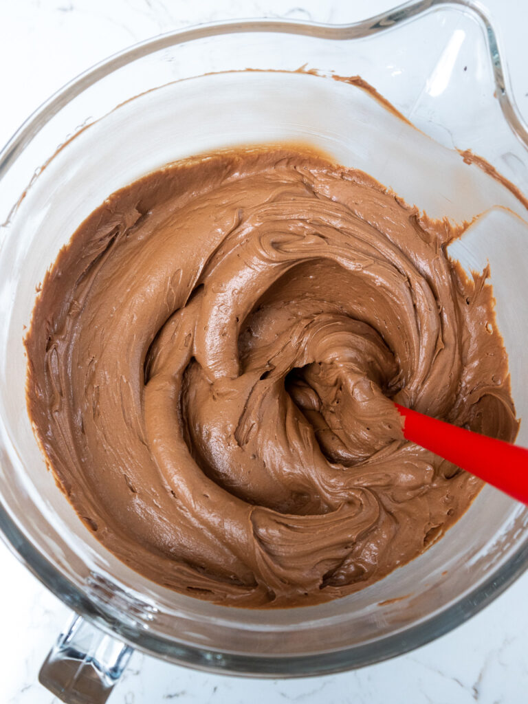 image of Nutella buttercream being mixed in a glass KitchenAid bowl