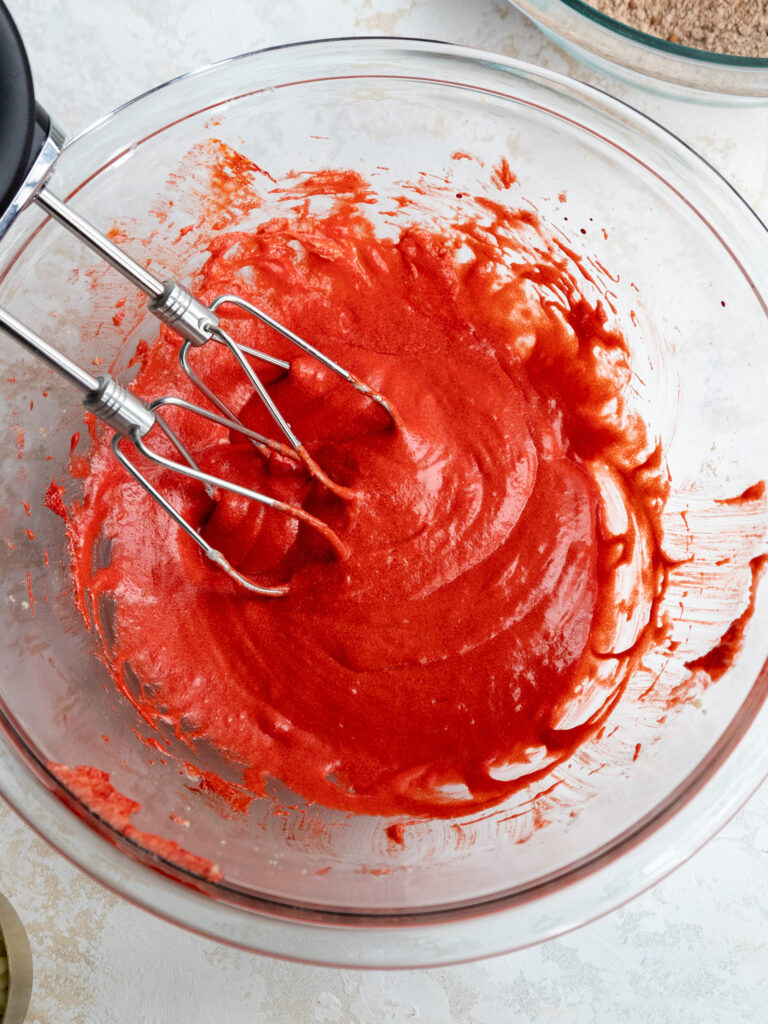 image of wet ingredients being mixed into red velvet crinkle cookie dough