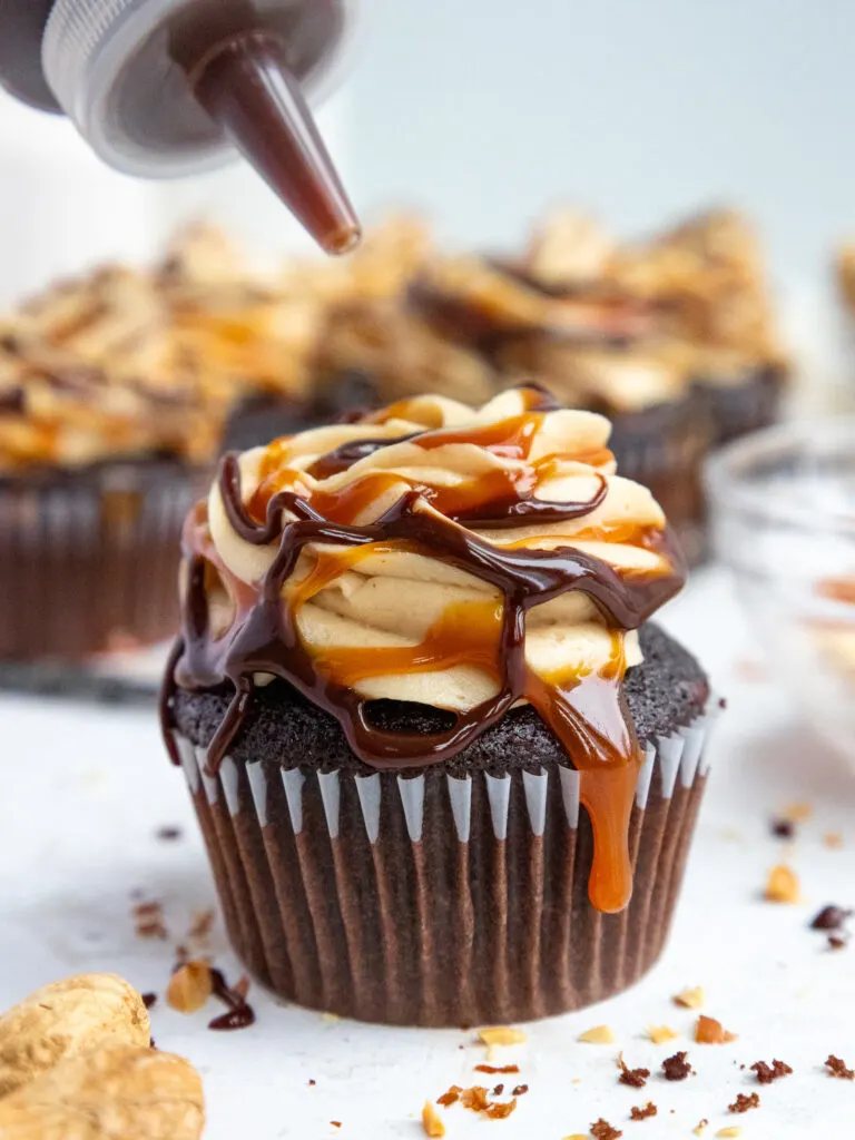 image of chocolate ganache being drizzled onto a snickers cupcake