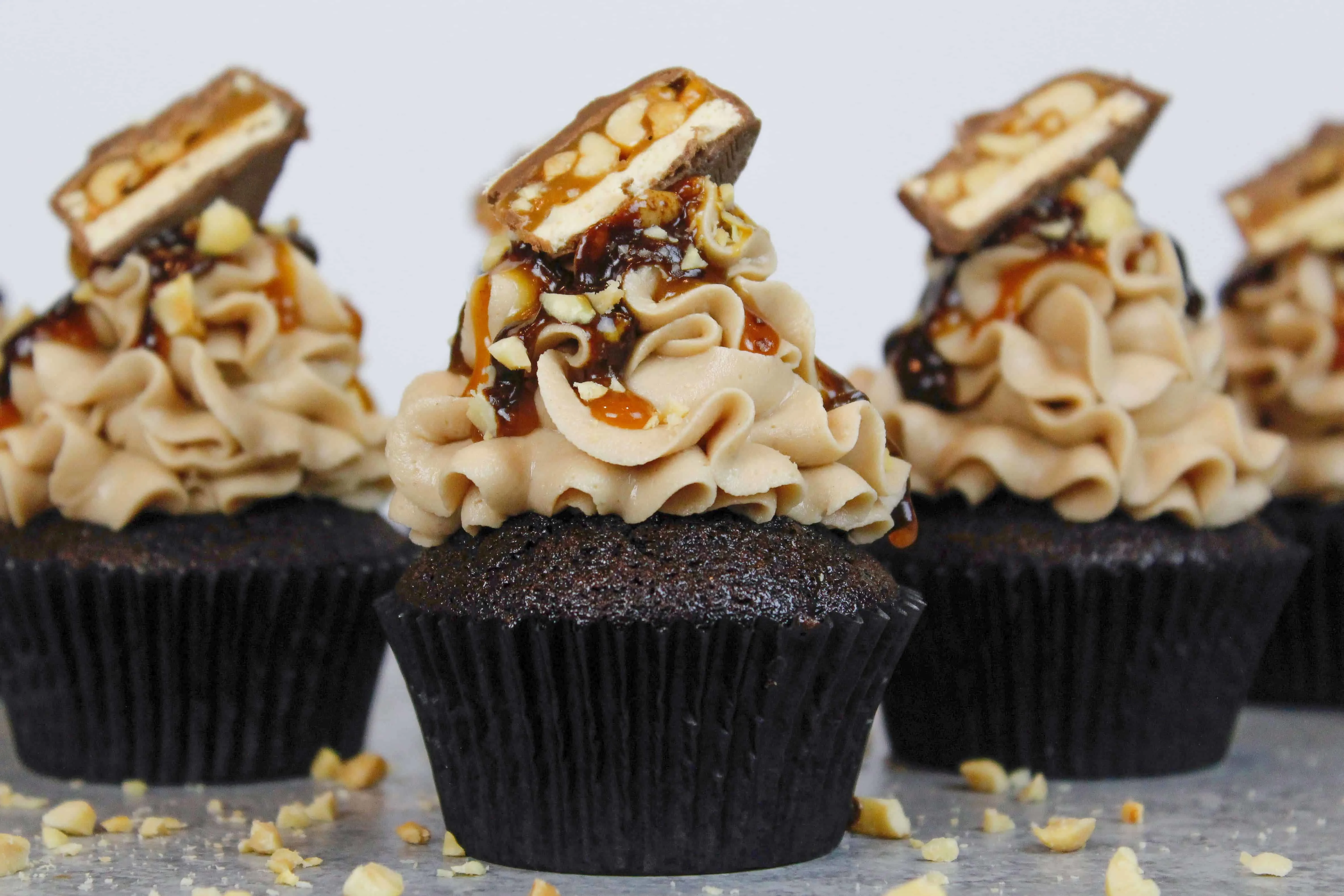 snickers cupcakes, made with chocolate cupcakes, peanut butter frosting, and a caramel and chocolate drizzle!