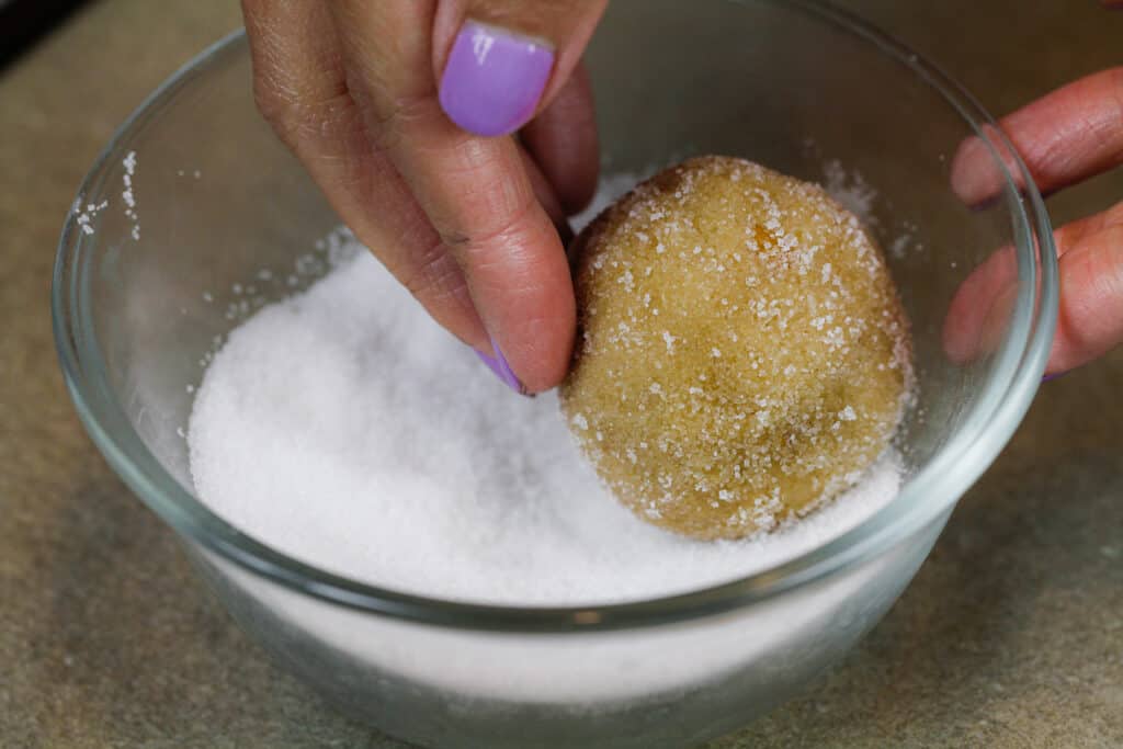 image of peanut butter cookie dough ball being rolled in granulated sugar