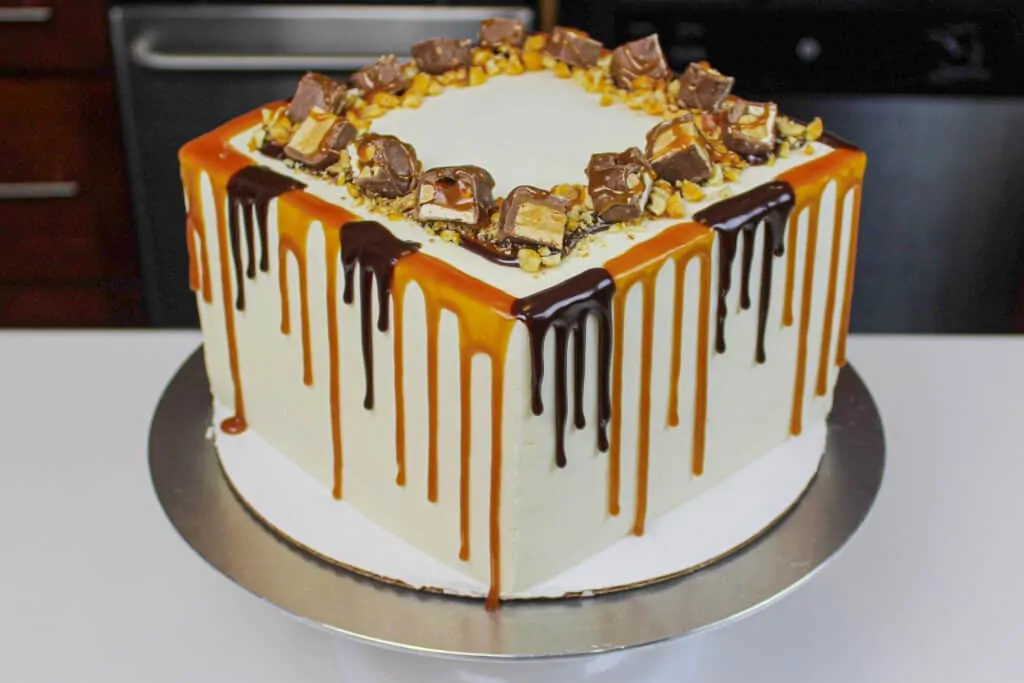 image of snickers drip cake with both a caramel and chocolate drip decoration