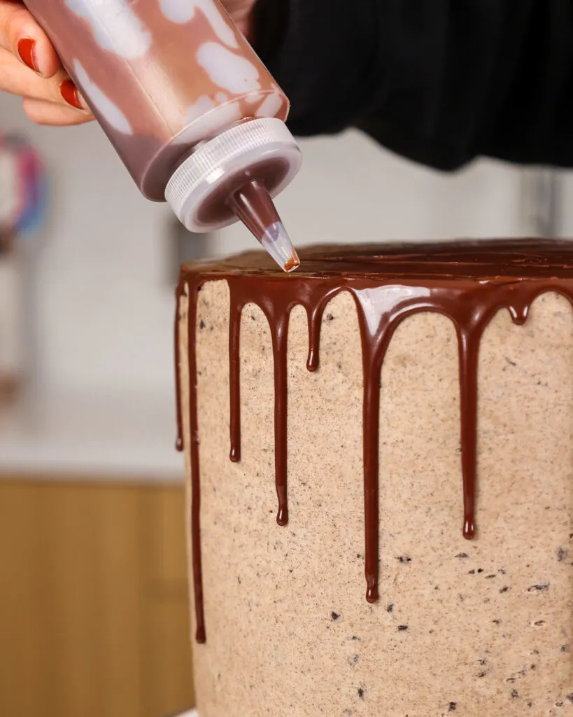 image of a chocolate ganache drip being added to an oreo brownie cake