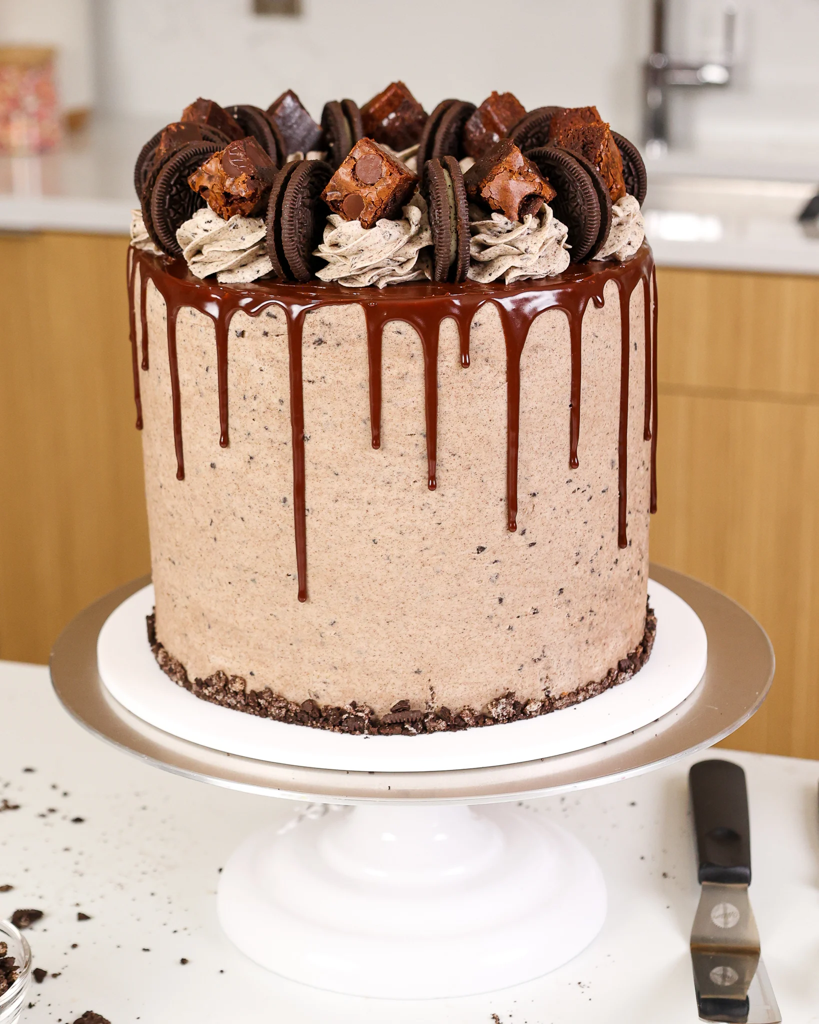 image of an oreo brownie cake that's been decorated with a chocolate drip and brownie bites
