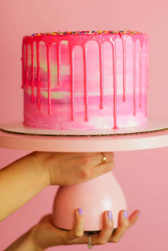 image of a beautiful pink drip cake, decorated with colored drips