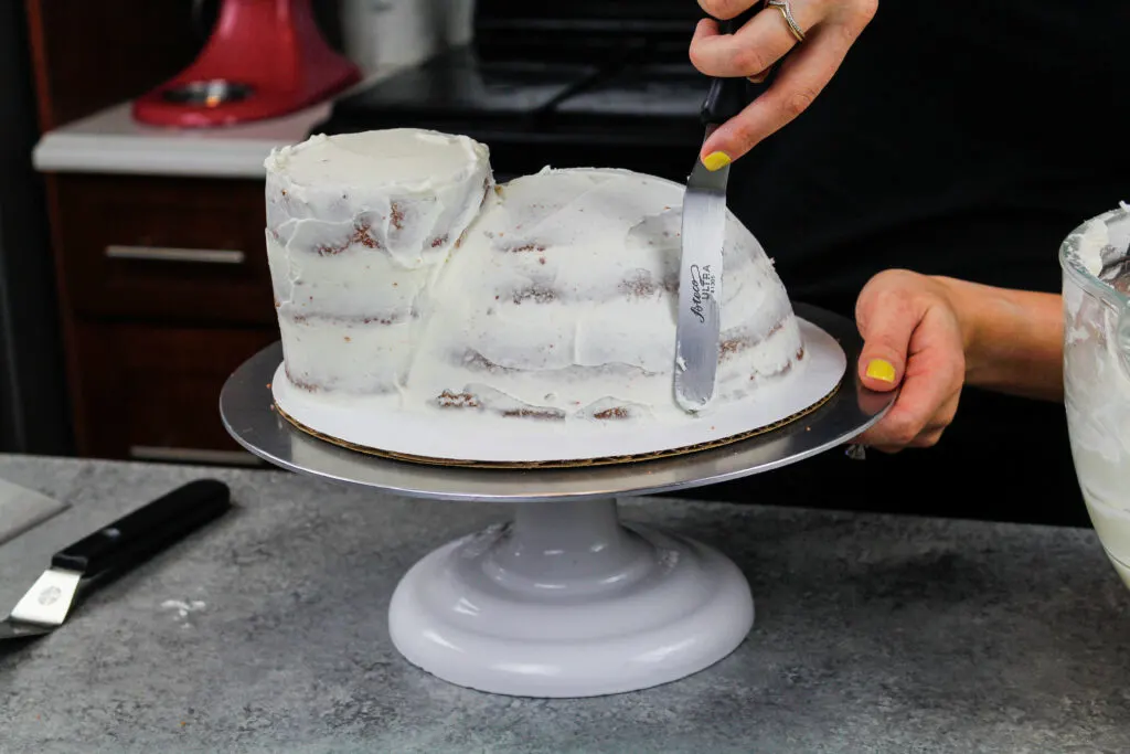 image of a crumb coat being spread on cake layers to make a hippo cake