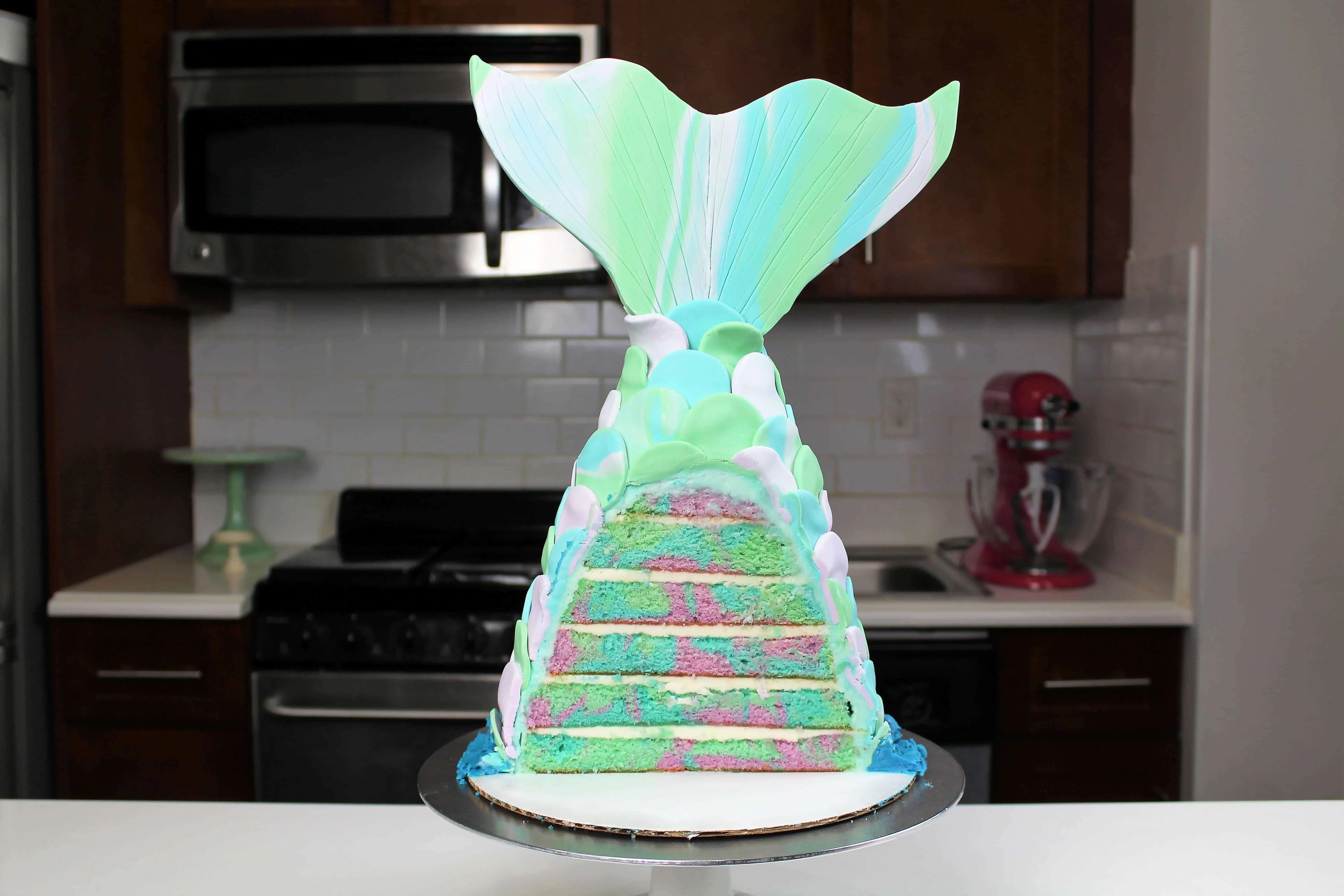 image of a beautiful pastel mermaid tail cake that's been cut into to show its pretty swirled cake layers