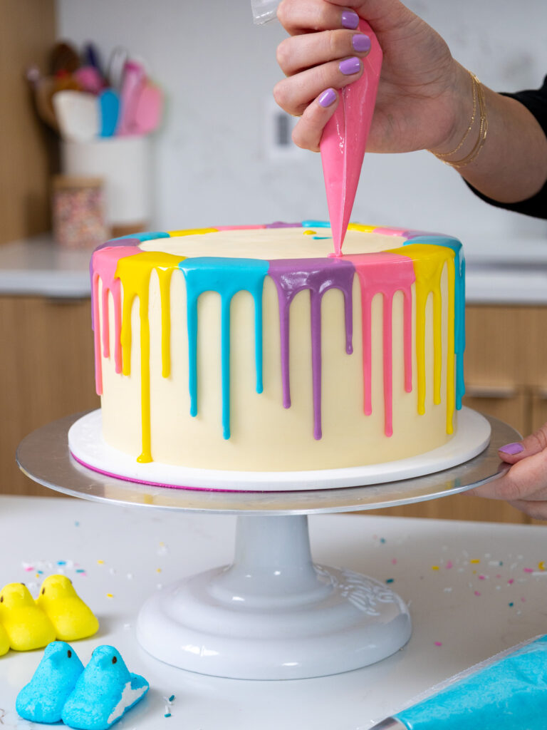 image of colorful drips being added to an Easter peeps cake that are blue, purple, pink, and yellow