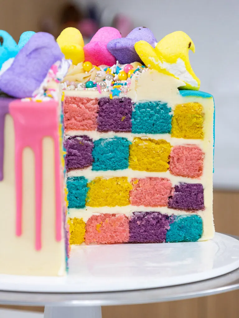 image of a Peeps drip cake that's been cut into to show it's blue, purple, pink, and yellow checkerboard cake layers