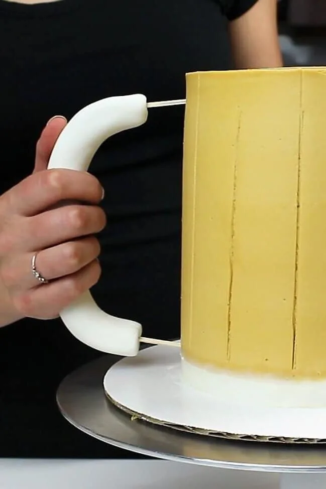 image of a fondant handle being pushed into a beer mug cake