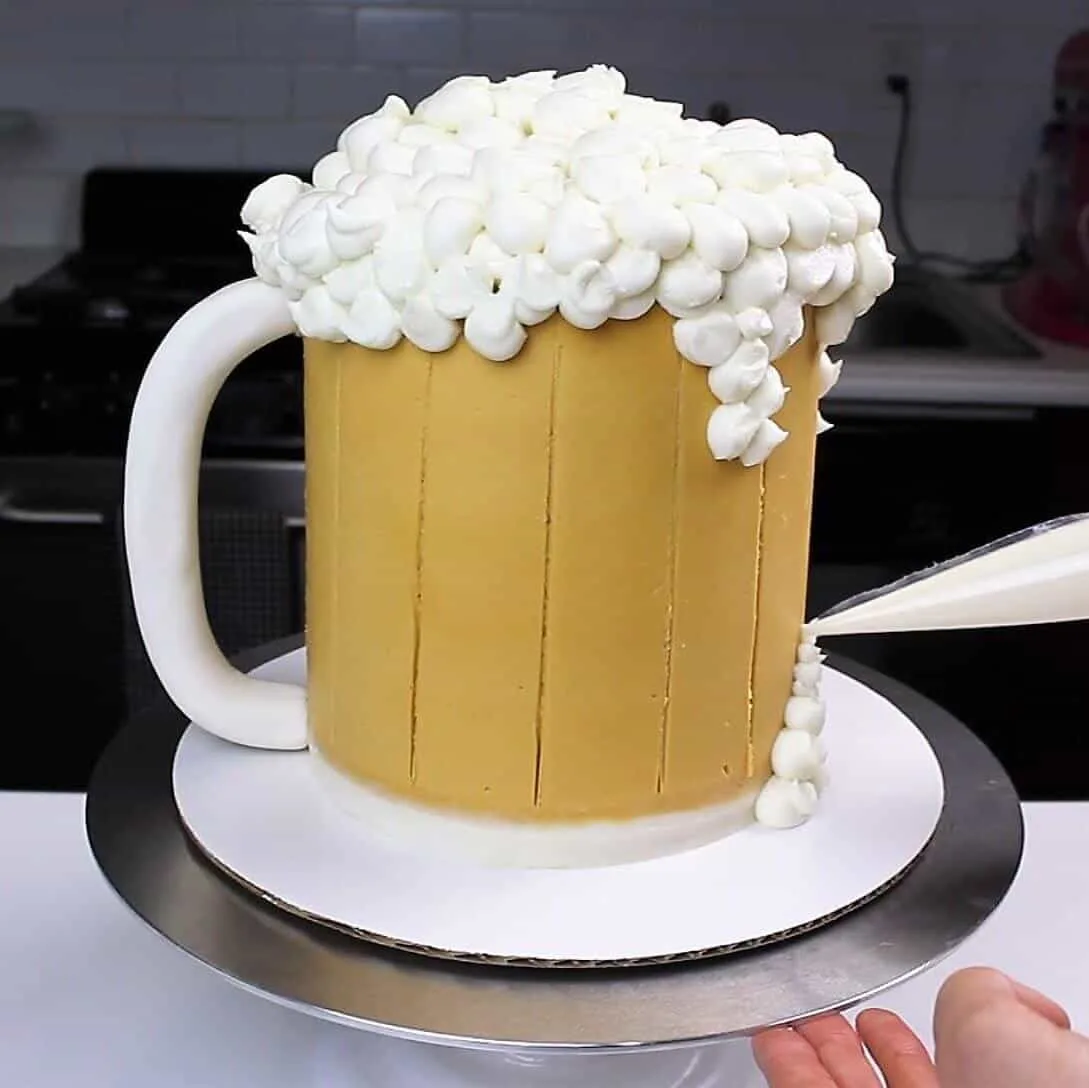 image of buttercream foam being piped onto a beer mug cake