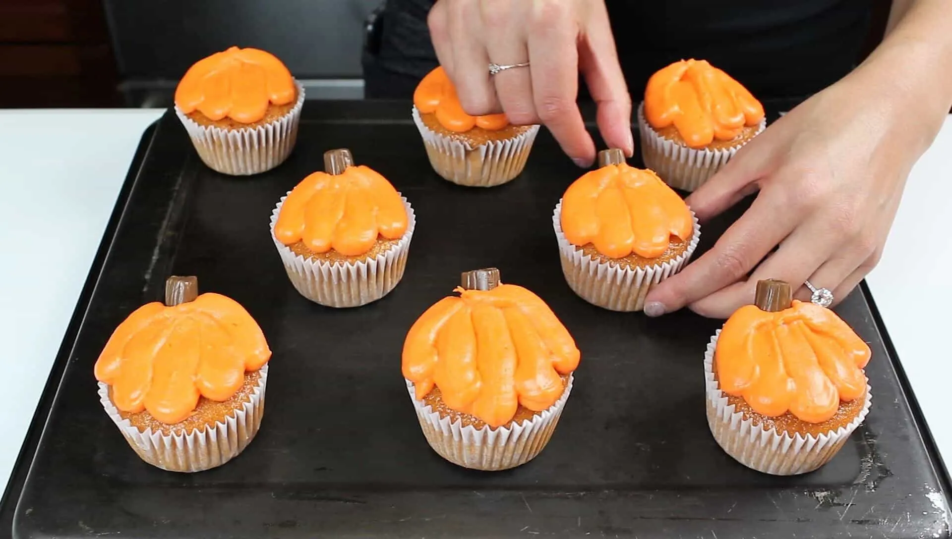  Image of adding tootsie roll stems to the pumpkin cupcakes