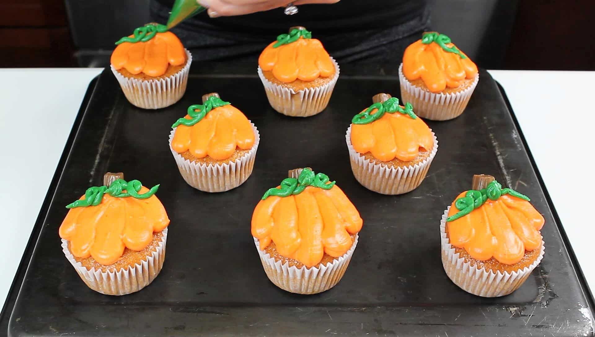 piping leaves onto the pumpkin cupcakes photo