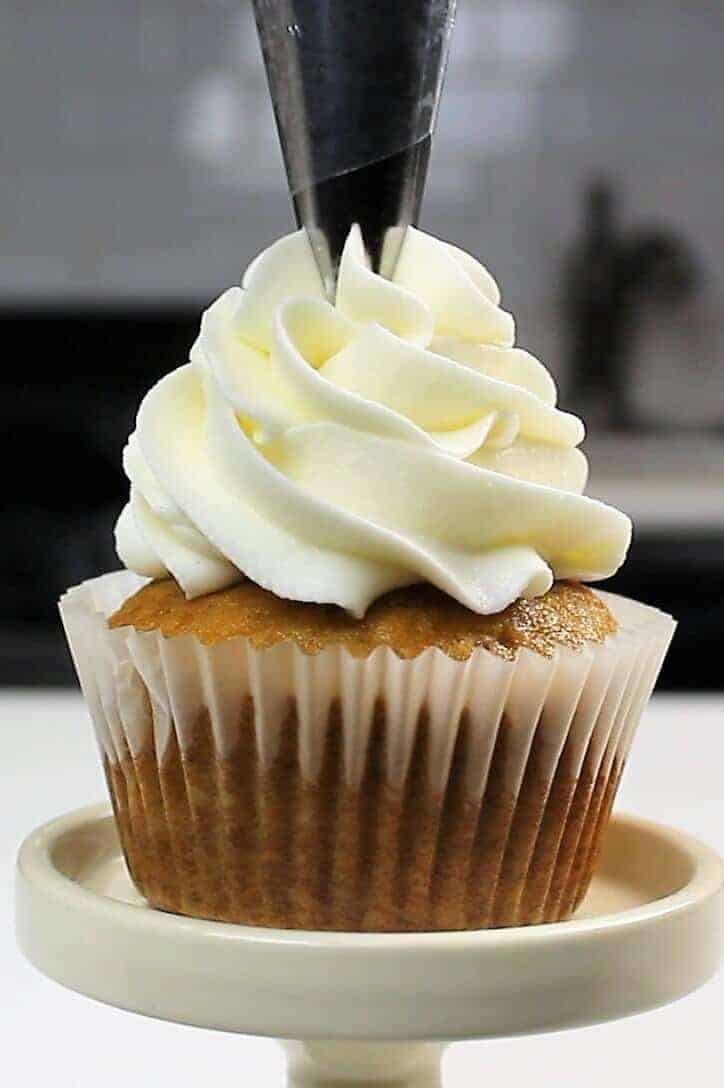image of cream cheese frosting being piped onto a cupcake