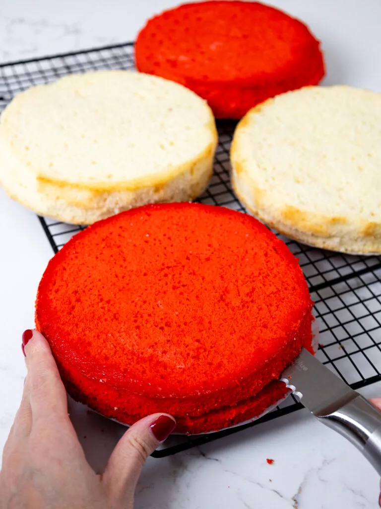 image of red and white cake layers being leveled and torted with a serrated knife