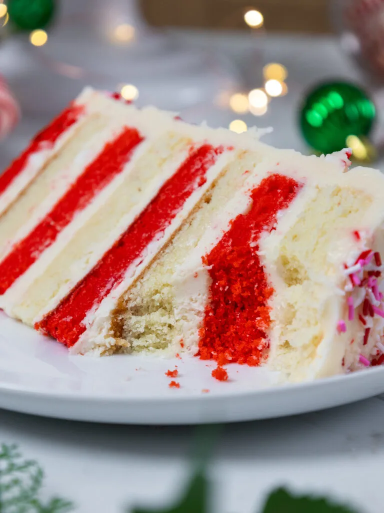 image of a slice of candy cane cake on a plate that's been cut into to show how tender the cake layers are.
