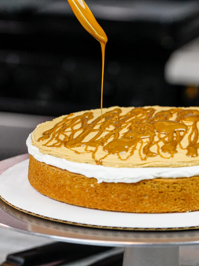 image of a cake being frosted with peanut butter cream cheese frosting  and a drizzle of peanut butter