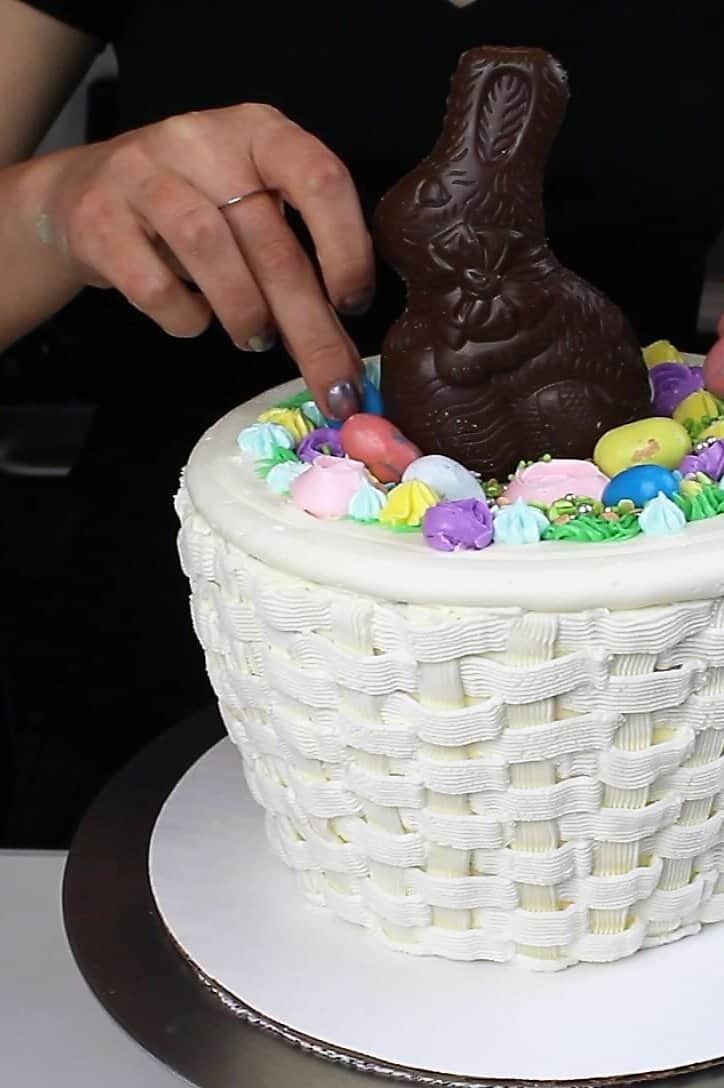 adding decoration to the top of the easter basket cake
