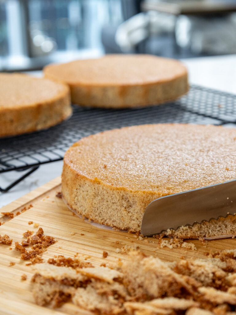 image of lotus biscoff cake layers being trimmed with a serrated knife