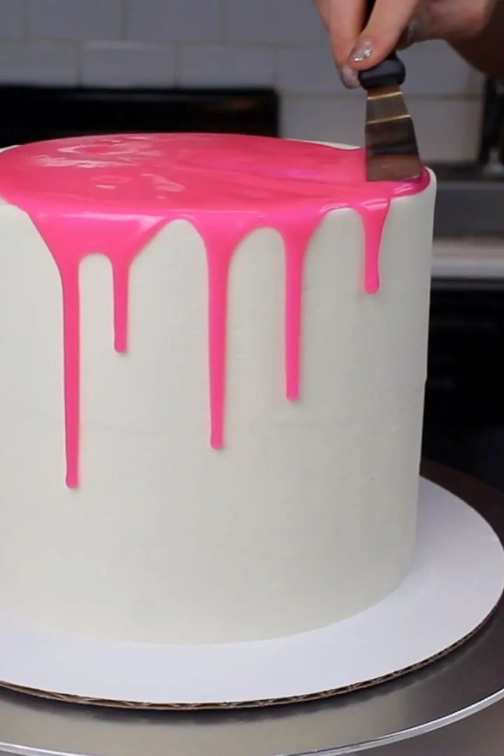 Photo of adding pink drips to a cake