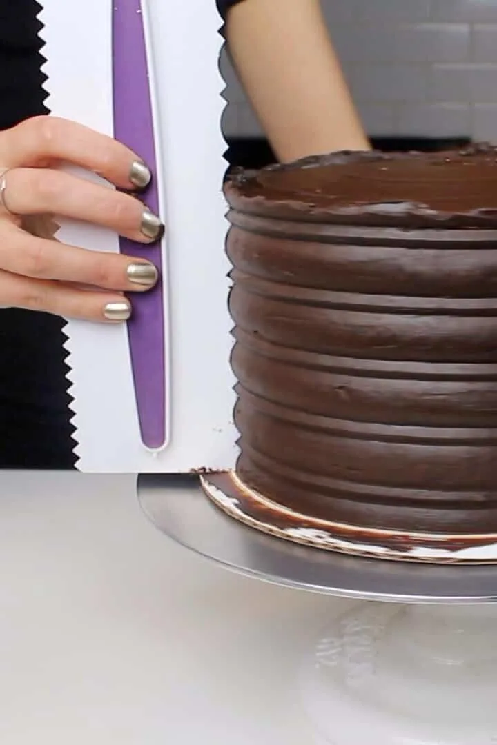 Using a frosting comb to add texture to the sides of this mothers day chocolate cake