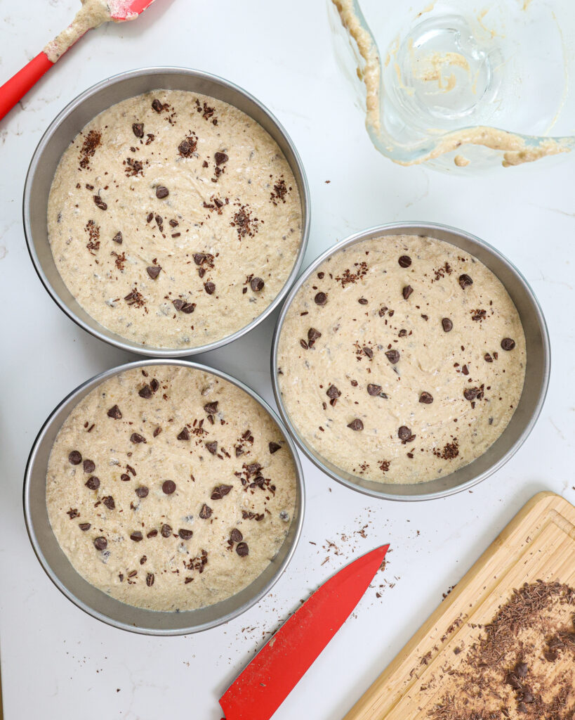 image of chocolate chip banana cake batter in 8-inch pans that are ready to be baked
