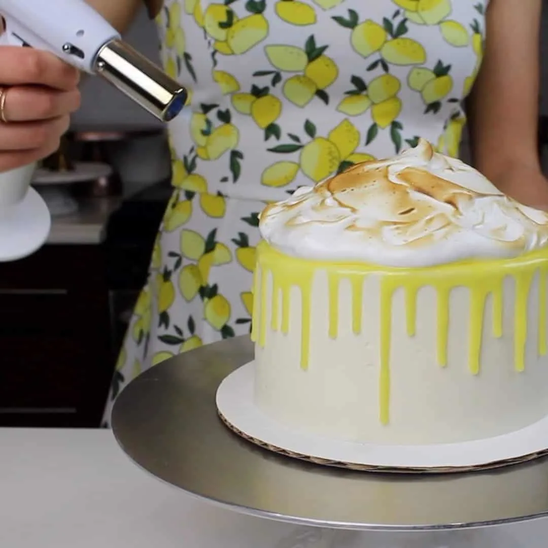 Photo of toasting meringue on top of a lemon meringue drip cake