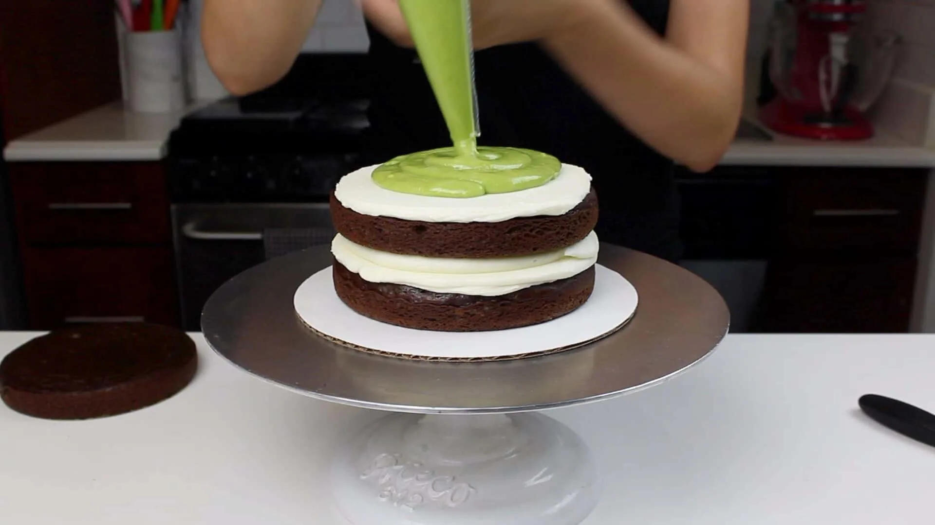 image of adding avocado frosting onto chocolate cake layer