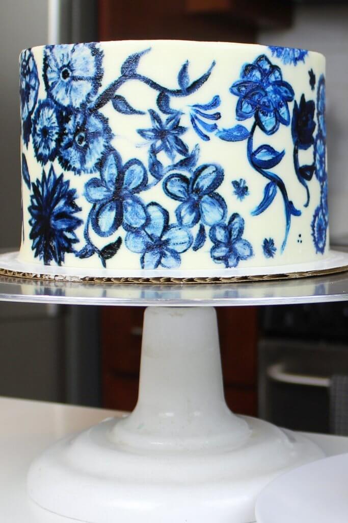 image of a painted buttercream cake decorated with a blue floral pattern
