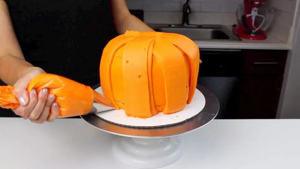 image of piping panels onto pumpkin cake using frosting