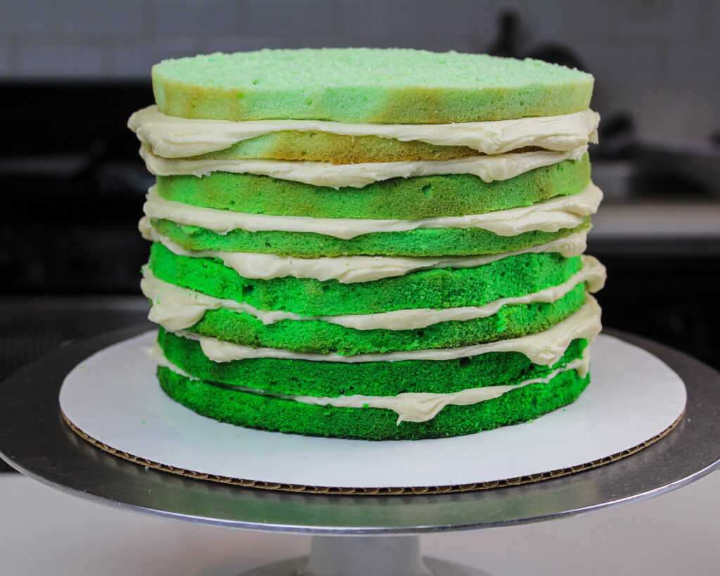 image of ombre green cake layers that have been stacked with frosting and are ready to be crumb coated