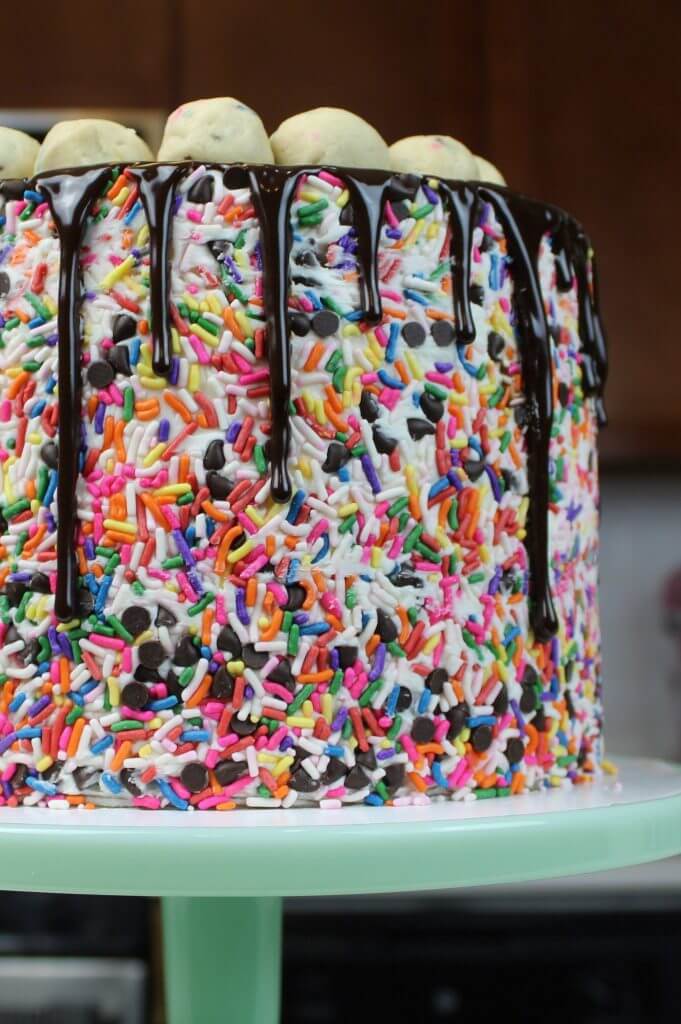 Image of a funfetti cookie dough cake, decorated with sprinkle sides and a chocolate drip