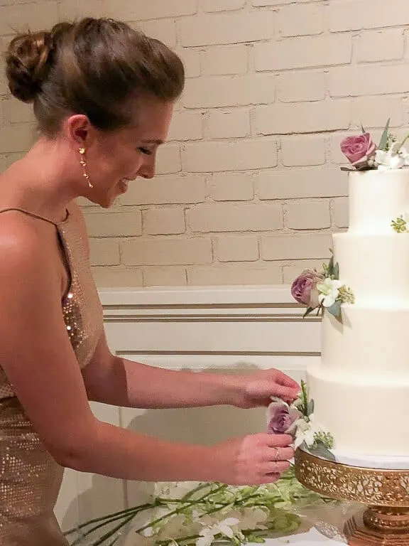 Photo of Chelsey White adding fresh flowers to a wedding cake