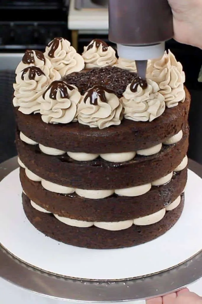 This naked chocolate cake is decorated with whipped chocolate buttercream, and a chocolate ganache drizzle over each swirl.